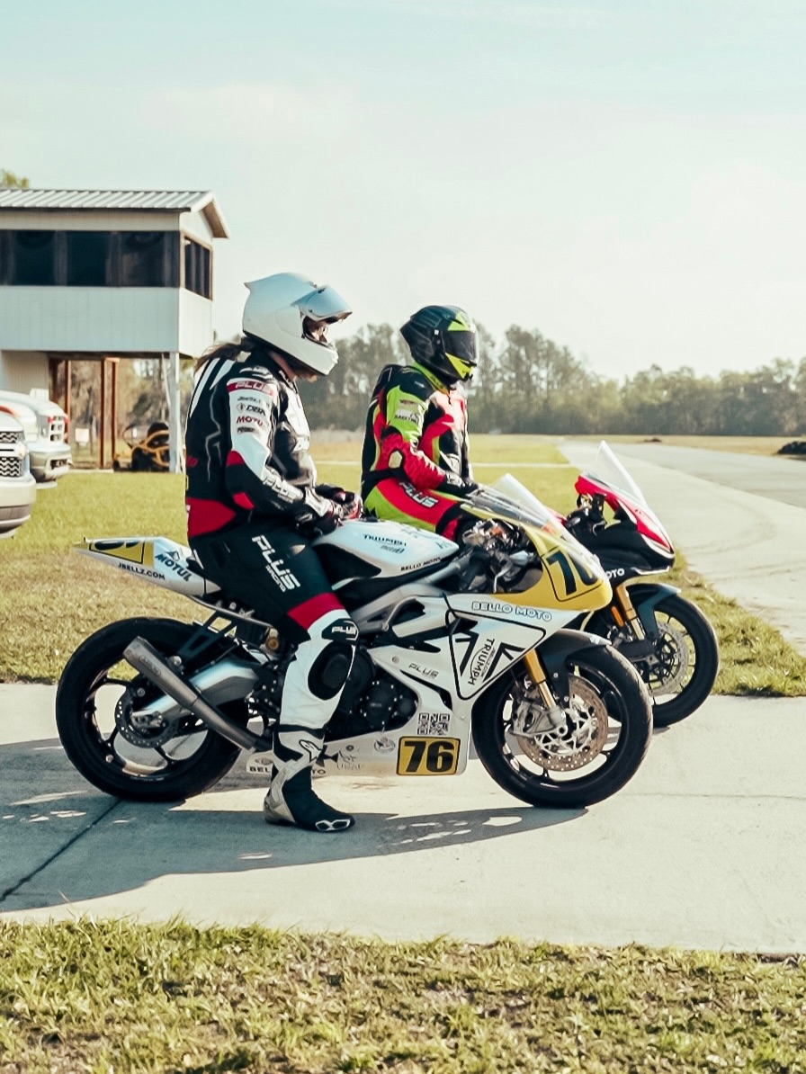 Dynasty Motoworks riders in race leathers on Triumph sport bikes in the paddock at a track day
