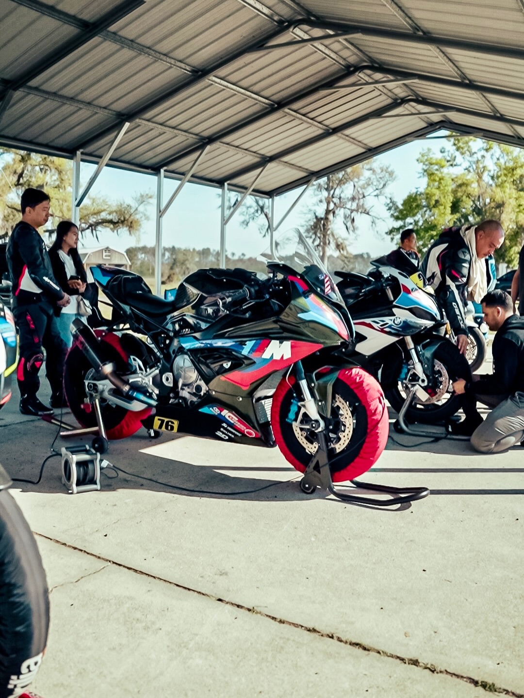 Dynasty Motoworks BMW M1000RR race bike on paddock stand with tire warmers at a race weekend